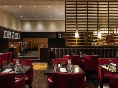 une salle à manger avec des tables et des chaises rouges dans l'établissement Mövenpick Hotel Frankfurt City Messe, à Francfort-sur-le-Main