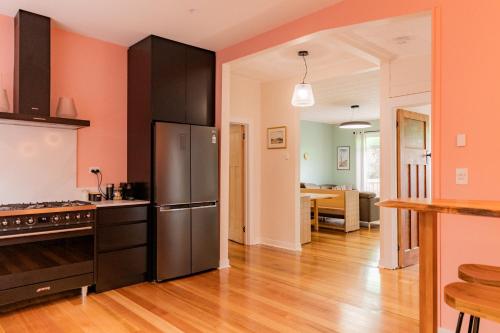 Una cocina con paredes naranjas y un refrigerador de acero inoxidable. en Bicheno Beach House, en Bicheno