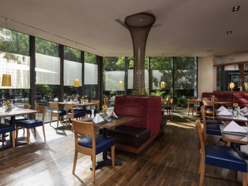 a restaurant with tables and chairs and windows at Mövenpick Hotel Münster am Aasee in Münster