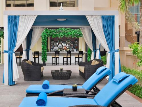 an outdoor gym with blue chairs and a table at Mövenpick Hotel Jumeirah Beach in Dubai