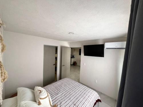 a bedroom with a bed and a flat screen tv at Acojedor departamento en el centro de Guadalajara in Guadalajara