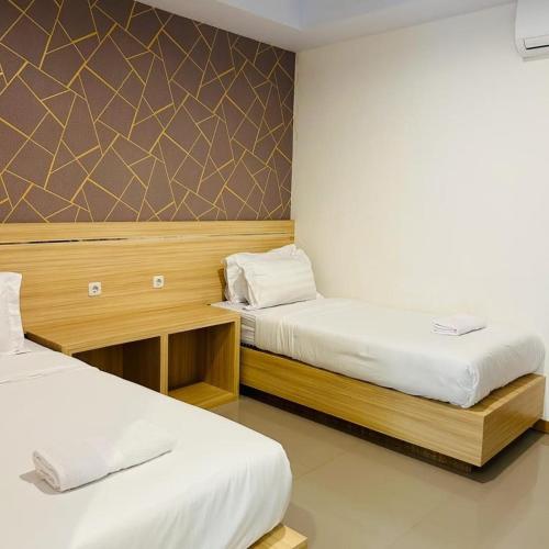 a bedroom with two beds and a wall at Wisma teluk bayur sidapore Tb in Lamobuang
