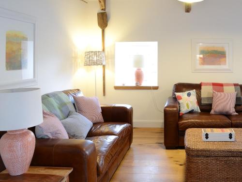 a living room with two leather couches and a table at The Byre in Rispond