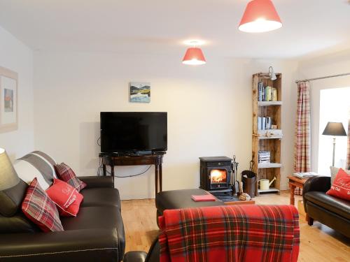 a living room with a couch and a stove at The Cottage in Rispond