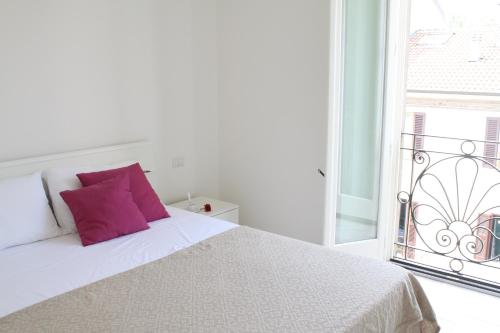 a white bed with a purple pillow and a window at meschihouse - Da Vinci 35 in Lecco