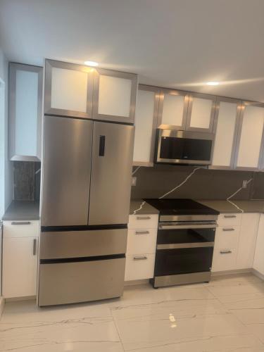 a kitchen with white cabinets and a stainless steel refrigerator at Contemporary Waterfront Condo in North Palm Beach