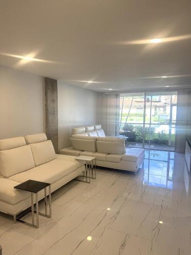 a living room with couches and tables and a large window at Exclusive Waterfront Condo in North Palm Beach