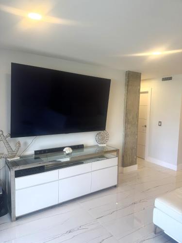 a living room with a large flat screen tv at Exclusive Waterfront Condo in North Palm Beach