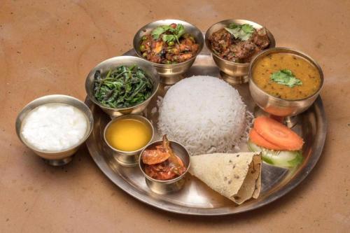 um prato de alimentos com arroz e diferentes tipos de alimentos em Hotel Good one em Pokhara