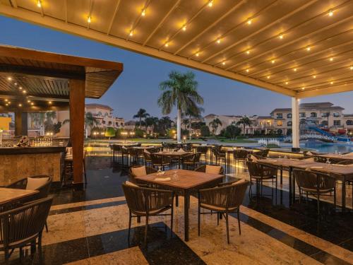 Un restaurante con mesas y sillas y una piscina. en Mövenpick Hotel Cairo - Media City, en Seis de Octubre