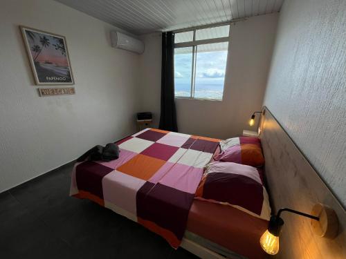 a bedroom with a bed with a colorful comforter at Airport Pamatai Room in Faaa