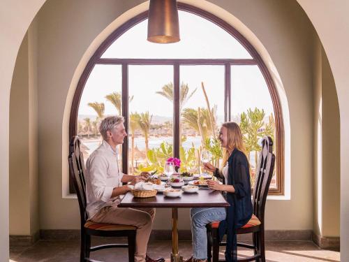 a man and woman sitting at a table with food at Movenpick Resort El Quseir in Quseir