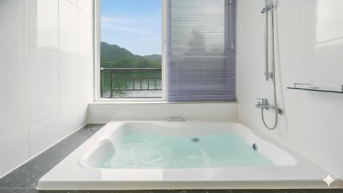 eine weiße Badewanne in einem Badezimmer mit Fenster in der Unterkunft Gapyeong Rialto Pension in Gapyeong
