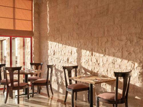 Grand Mercure Petra في وادي موسى: مجموعة طاولات وكراسي في مطعم
