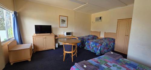 ein Zimmer mit zwei Betten, einem Tisch und einem Fernseher in der Unterkunft Sportsmans Arms Hotel Motel Deniliquin in Deniliquin