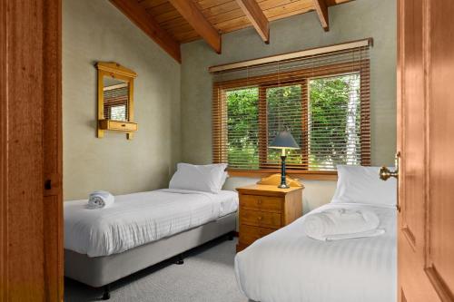 two beds in a room with a window at The Wolery - Lakeside Jindabyne in Jindabyne