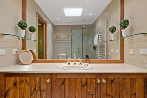 a bathroom with a sink and a shower and a mirror at The Wolery - Lakeside Jindabyne in Jindabyne