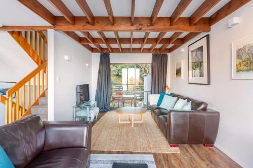 een woonkamer met een leren bank en een tafel bij The Twins in Queenstown