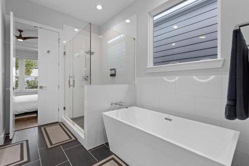une salle de bain blanche avec une baignoire et une douche dans l'établissement Spacious Sleek Modern Art Deco Gem in Downtown HTX, à Houston