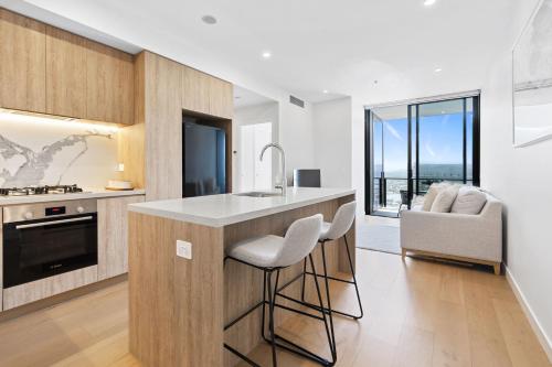 a kitchen with a counter with stools and a sink at Modern 1 Bedroom Unit at The Casino - NO PARKING - Q Stay in Gold Coast