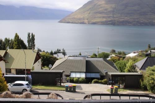 a house with a car parked next to a body of water at The Cameron Bothy in Queenstown