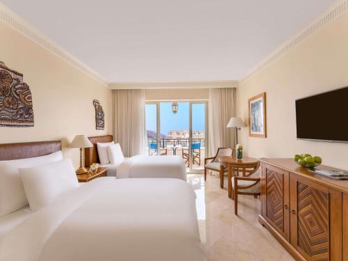 a hotel room with a bed and a television at Mövenpick Resort & Residences Aqaba in Aqaba