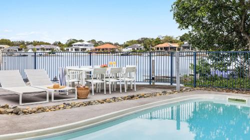 a patio with a table and chairs next to a pool at Pandanus - Spacious Waterfront Escape - Holiday Yamba in Yamba