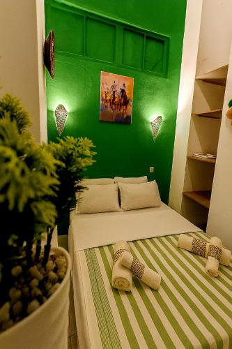 a green room with a bed with two slippers at Kasbah Nights Retreat and best breakfast offers - Entire House in Tangier