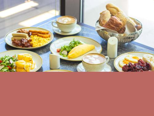 a table with plates of food and cups of coffee at Admiral Hotel Manila - MGallery Collection in Manila