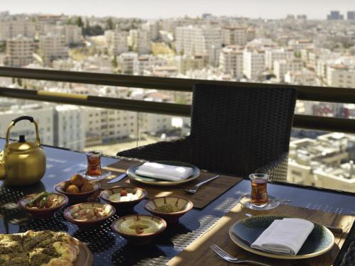 a table with plates and bowls of food on a balcony at Mövenpick Hotel Amman in Amman