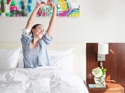 a woman laying in bed with her arms in the air at Mövenpick Hotel Amman in Amman