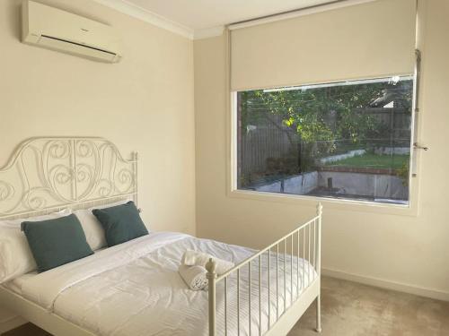 a bedroom with a bed and a large window at Stylish 4BR Home in the Centro of Glen Waverley in Black Flat