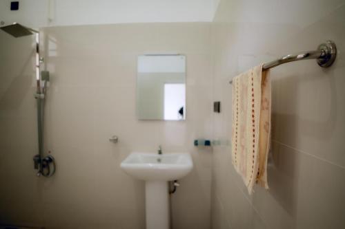 a white bathroom with a sink and a mirror at Sea wind in Mirissa