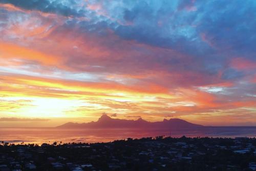 einen Sonnenuntergang über der Stadt mit Bergen im Hintergrund in der Unterkunft Luxury Eden & SPA - private jacuzzi - Sunset lagoon view - pool - Wifi in Punaauia