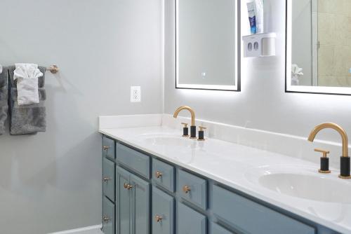un baño con dos lavabos y dos espejos en Modern Escape Steps from FedEx Field & Near DC, en Largo