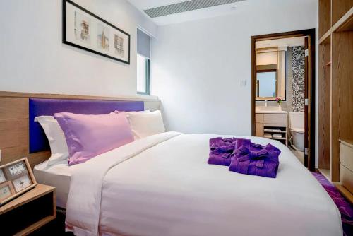 a bedroom with a large white bed with purple pillows at Hotel Purple Hong Kong in Hong Kong