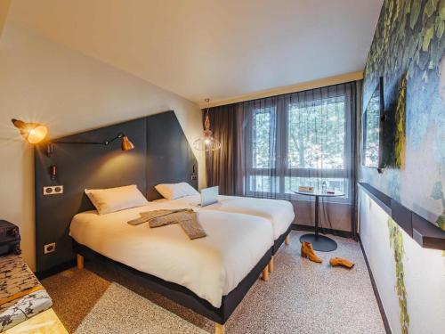 a hotel room with two beds and a large window at Ibis Styles Rouen Centre Rive Gauche in Rouen