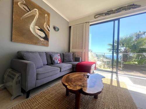 a living room with a couch and a table at Villa Aqua at Palm Beach in Waiheke Island