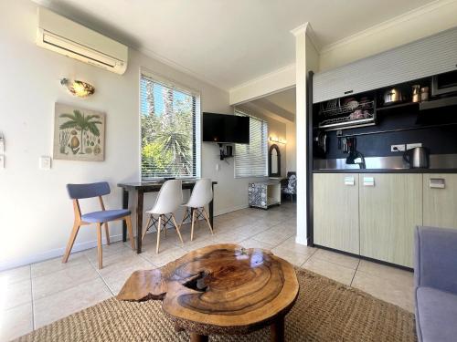 a living room with a table and a kitchen at Villa Aqua at Palm Beach in Waiheke Island