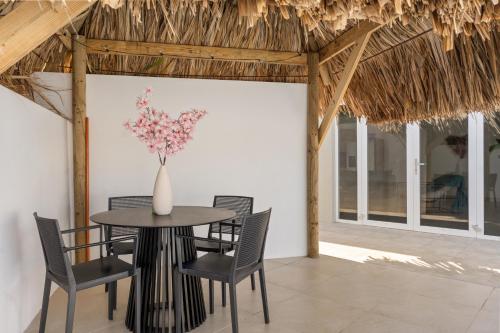 - une salle à manger avec une table, des chaises et un vase fleuri dans l'établissement Luxe Huis Met Privzwembad Villapark Fontein, à Fontein