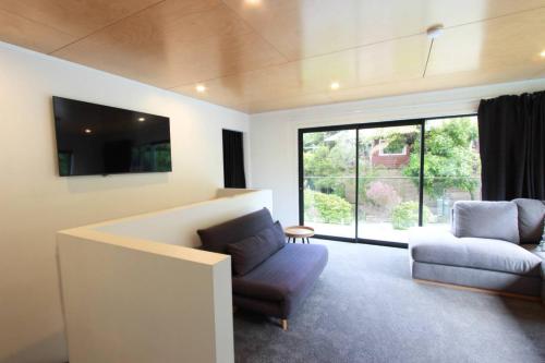 a living room with a couch and a chair and a window at Modern Tata Beach Escape - Spacious New Retreat in Tata Beach