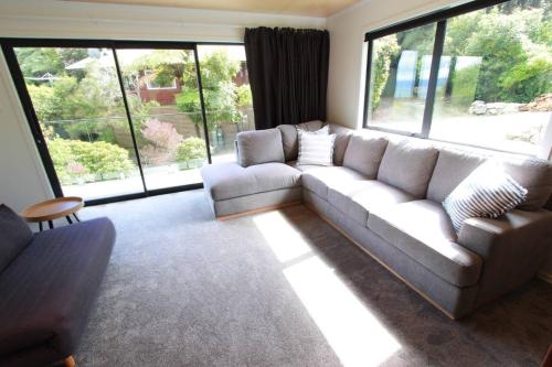 a living room with a couch and large windows at Modern Tata Beach Escape - Spacious New Retreat in Tata Beach