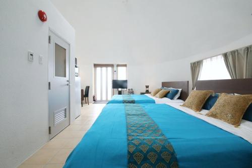 2 große Betten in einem Zimmer mit blauer Bettwäsche in der Unterkunft URUMA DOME Neptune9 in Uruma