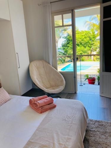a bedroom with a bed with a chair and a pool at villa Whakata Saint Leu in Saint-Leu