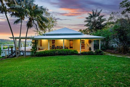 a yellow house with a lawn in front of it at Hinterland Retreat l Fire Pit Scenic Views l Nova Escapes in Goonengerry