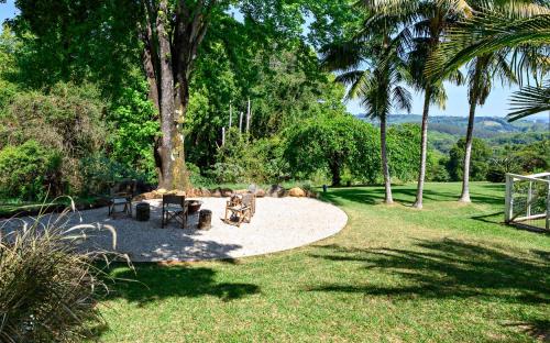 a garden with a fire pit and palm trees at Romantic Escape l Firepit & Views l Nova Escapes in Goonengerry
