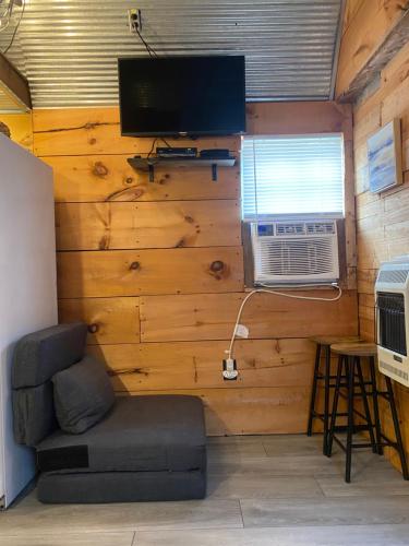 Habitación con pared, TV y silla. en Cozy little Cabin, en Van Buren
