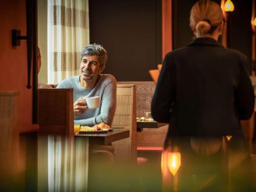 a man sitting at a table with a cup of coffee at Fairmont Chicago Millennium Park in Chicago