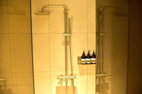 a bathroom with a shower with bottles on a shelf at HOTEL THE DESIGNERS LYJ SUITE YEOKSAM in Seoul
