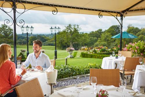 a man and woman sitting at a table in a restaurant at South Lodge in Lower Beeding